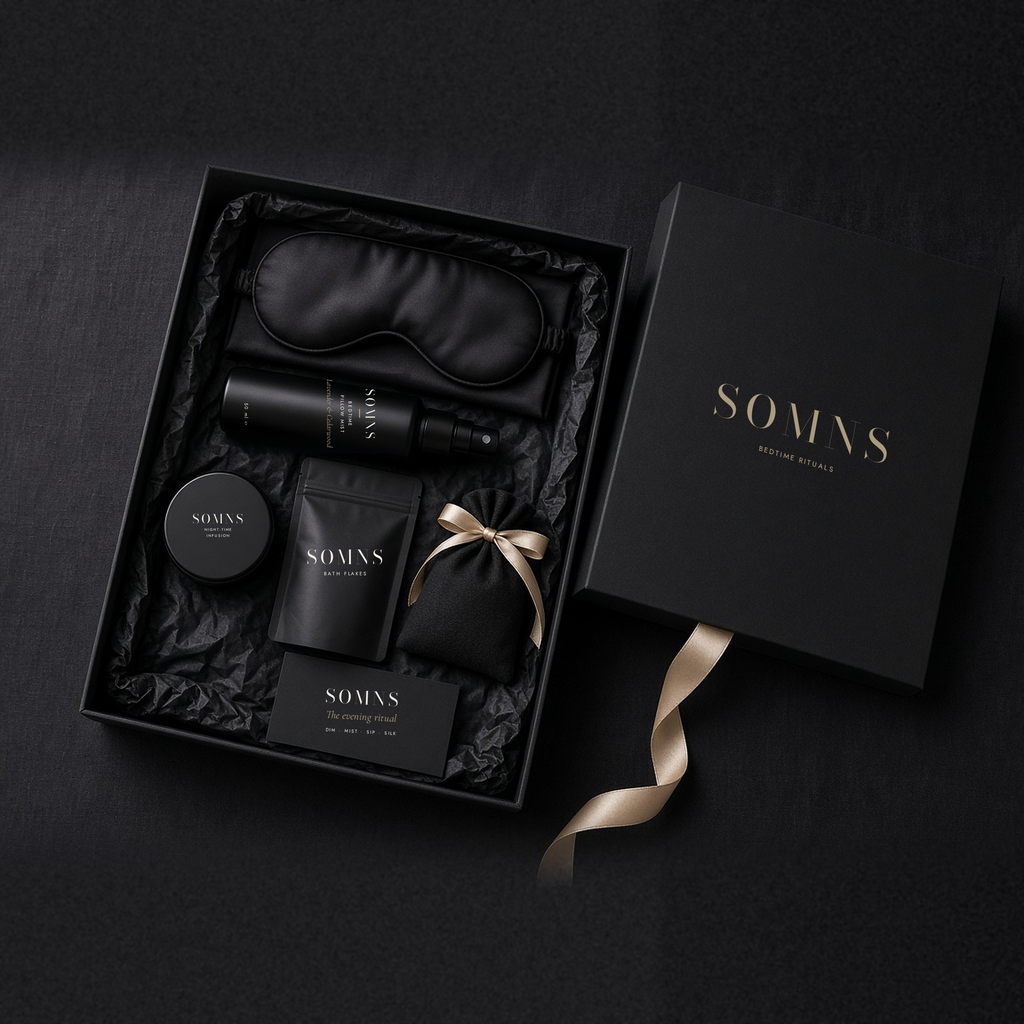 Opened SOMNS Midnight Silk box on black tissue with the pillow mist, silk eye mask, tea tin, bath flakes and ritual card inside